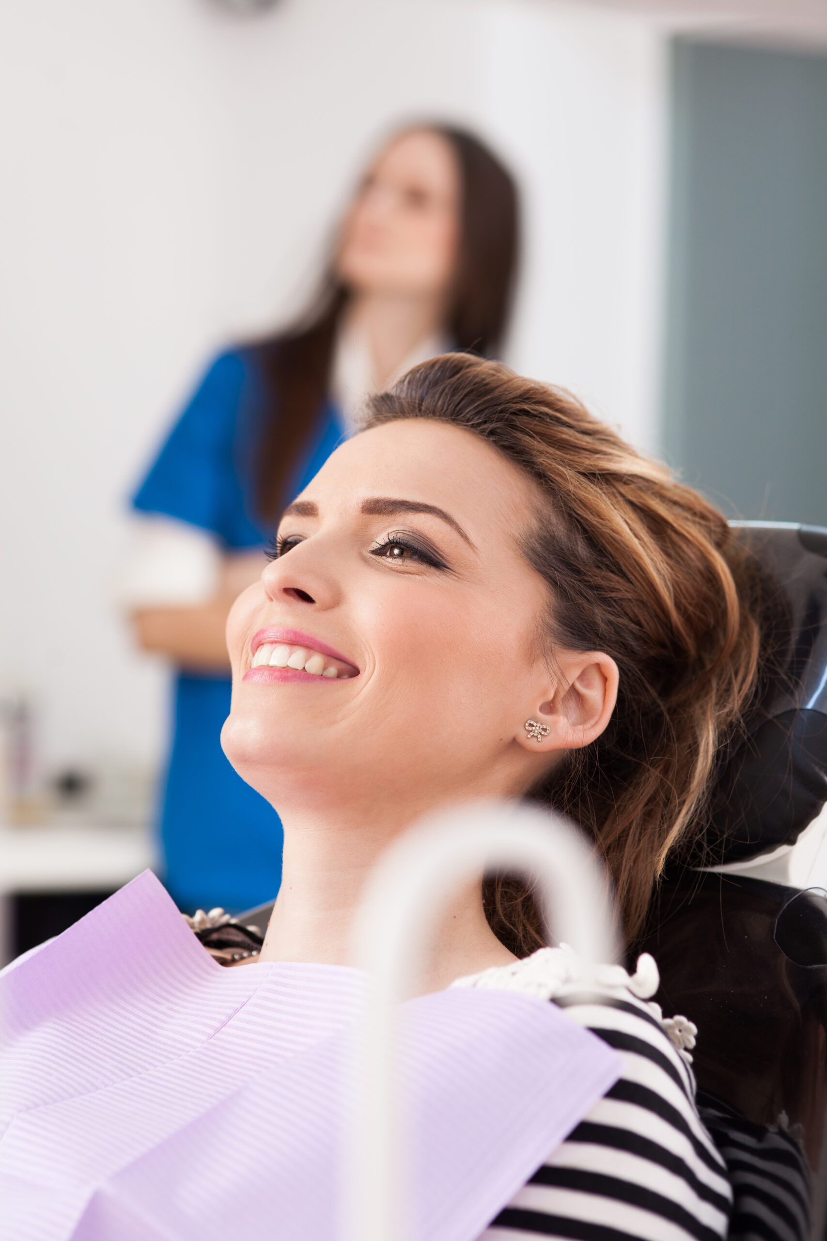 Closeup of a smiling woman patient waiting to be checked up with the nurse in the background