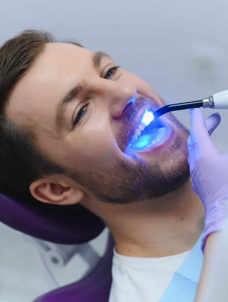 Closeup portrait patient in dental office - ultraviolet light equipment.