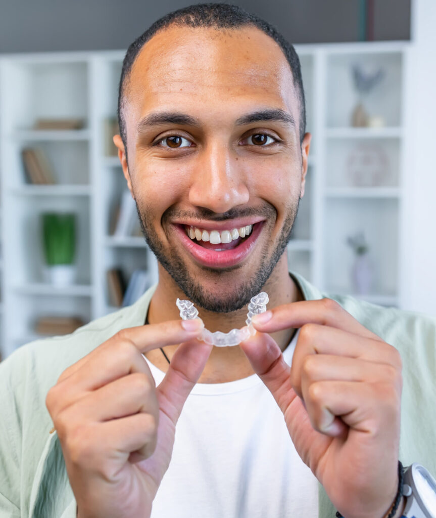 Adult man putting transparent braces for dental correction. holding invisible orthodontic retainer and aligner. Plastic braces dentistry to straighten teeth