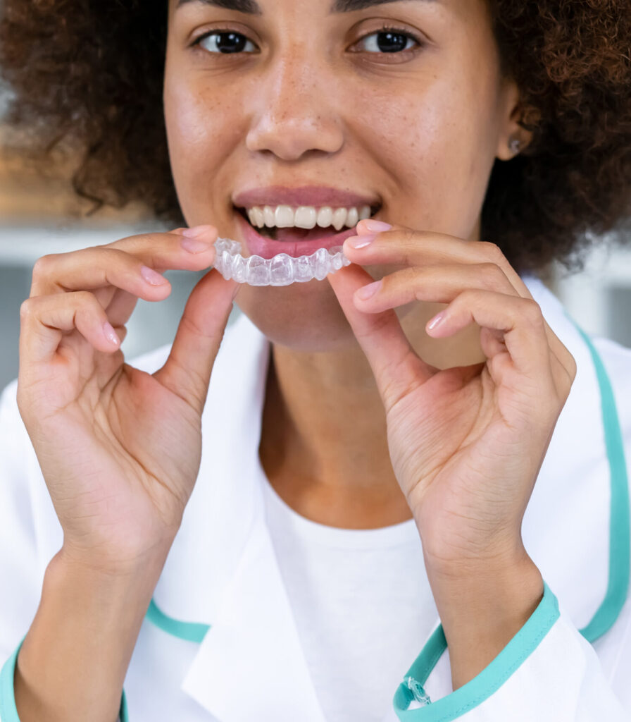 Skilled dentist showing how to wear clear aligners for professional teeth correction in contemporary stomatology clinic