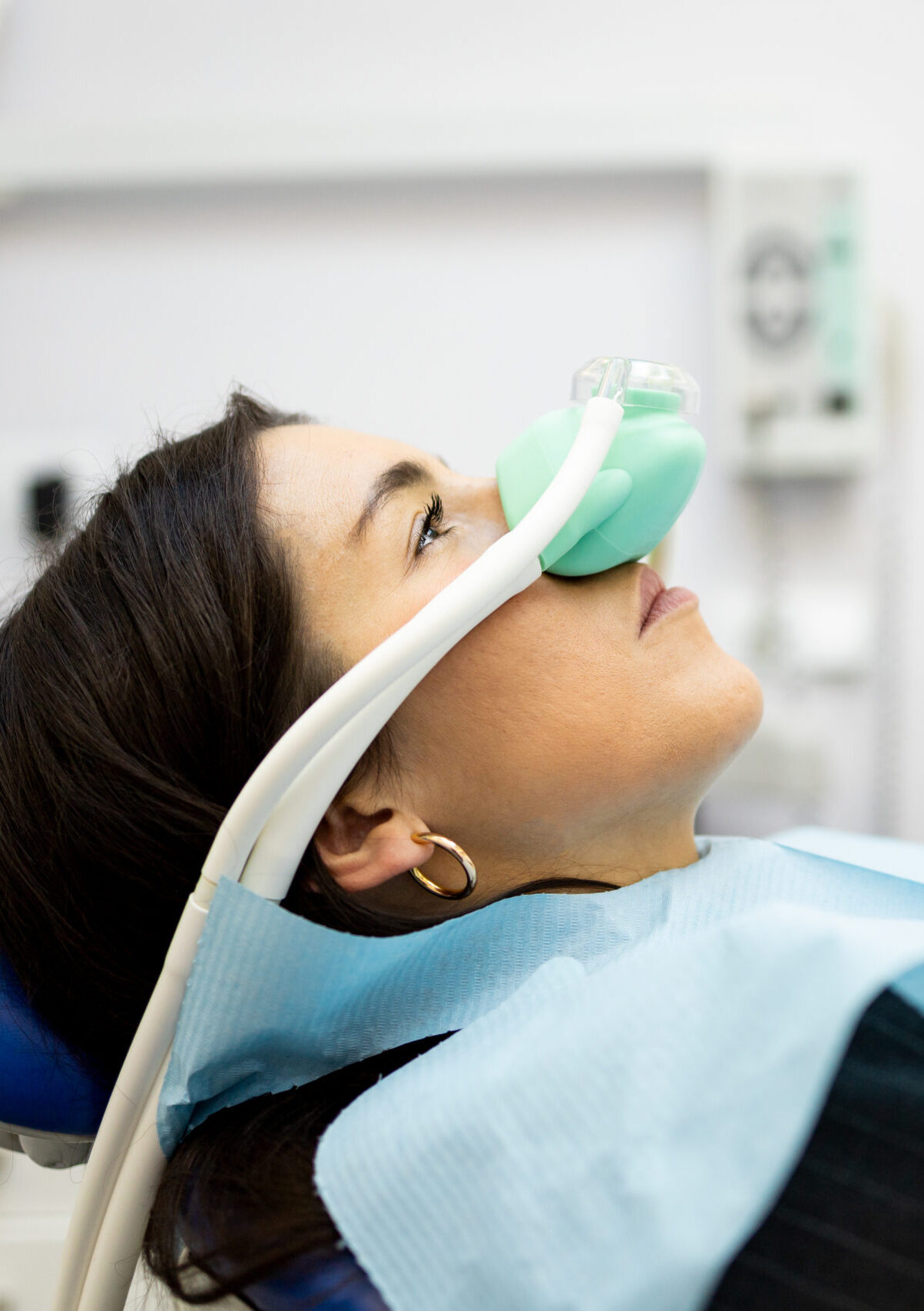 An adult woman sits in a dentist's office wearing a nasal mask to inhale nitrous oxide. Dentist fear concept. Feeling of relaxation with laughing gas. Visit a dentist with relaxation.
