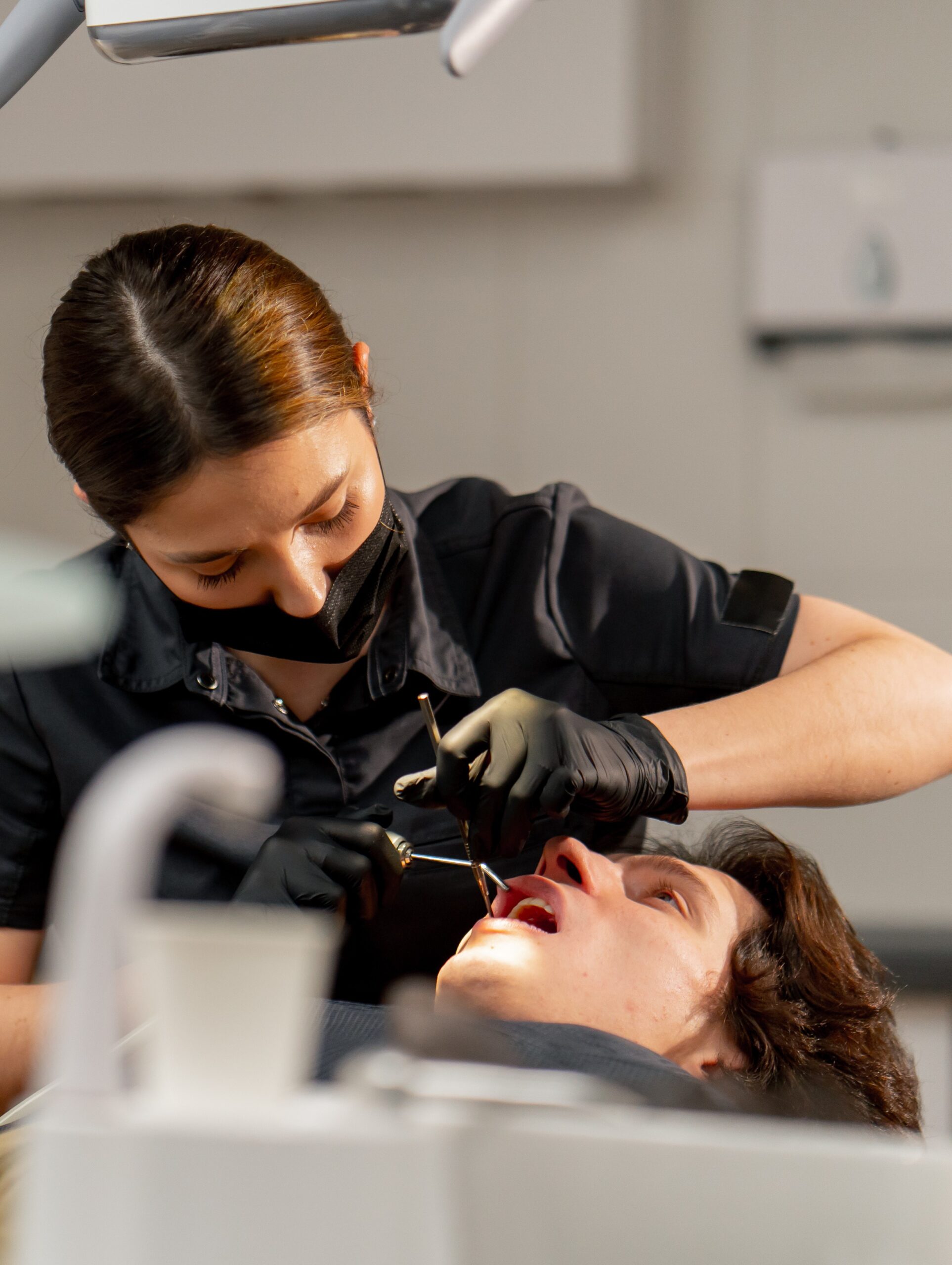 in the dental office girl doctor examines the oral cavity using a mirror and a machine with air