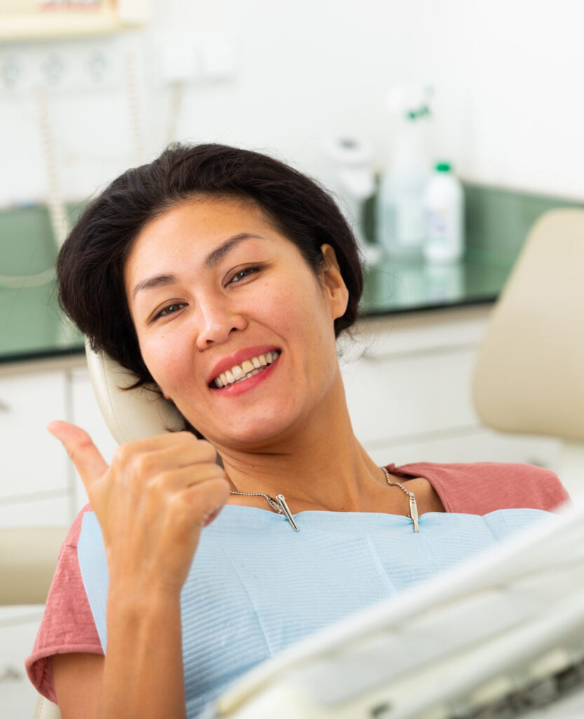 Portrait of a satisfied asian woman patient sitting in a dental chair in the clinic office