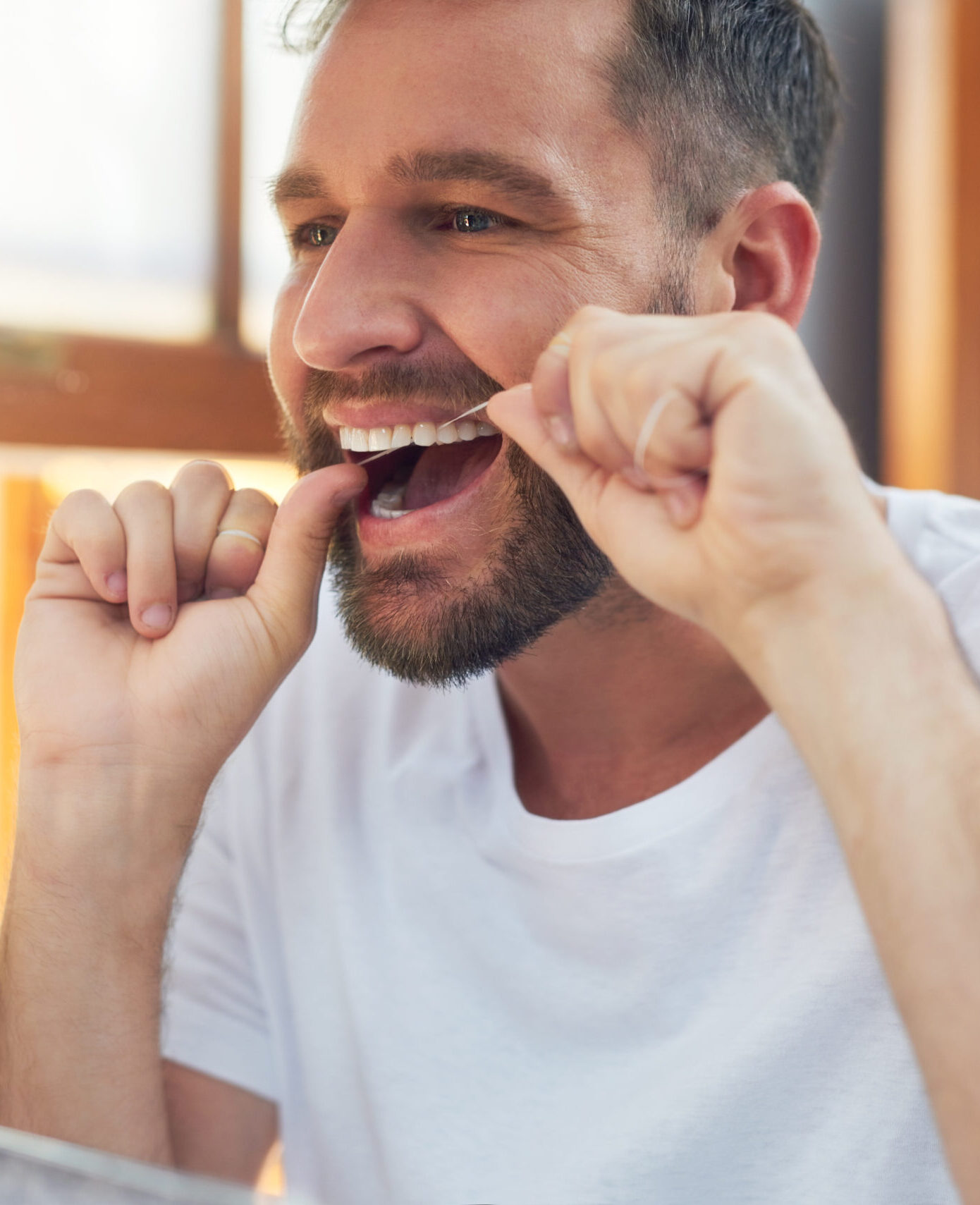 Man, teeth and flossing with morning routine in home for grooming, oral care and hygiene for wellness. Male person, reflection and mouth for dental health, fresh breath and bathroom with confidence.