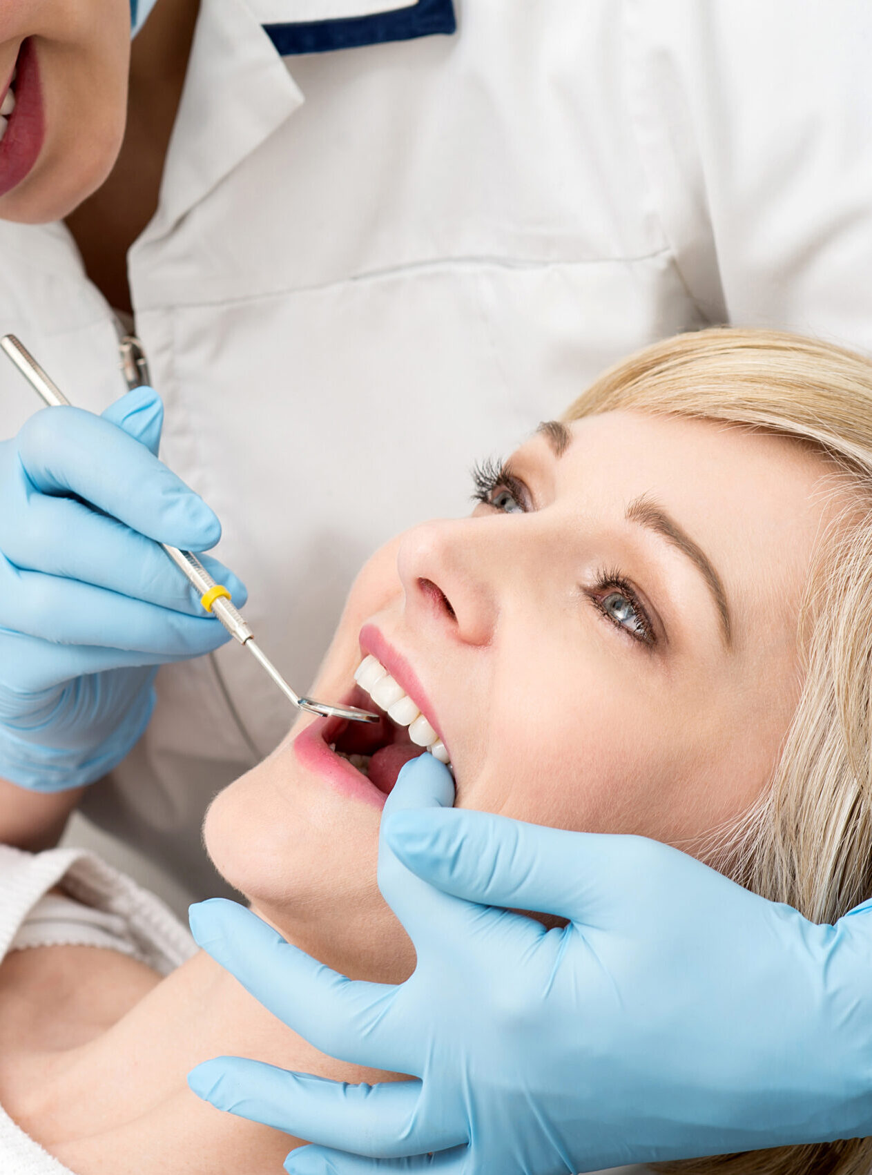 Female dentist examining teeth using mirror in clinic