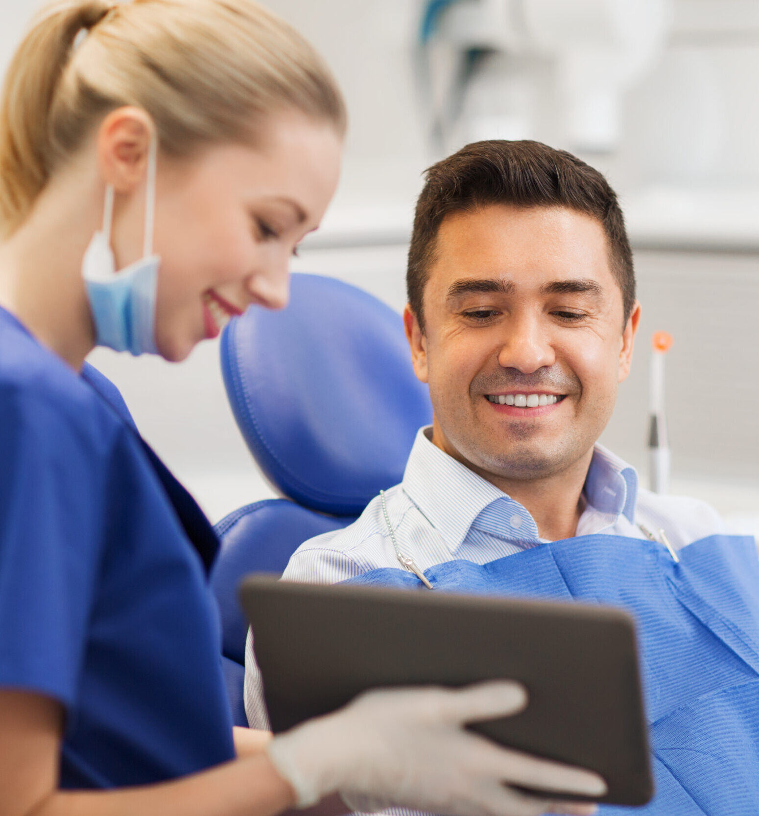 people, medicine, stomatology and health care concept - happy female dentist showing tablet pc computer to male patient at dental clinic office