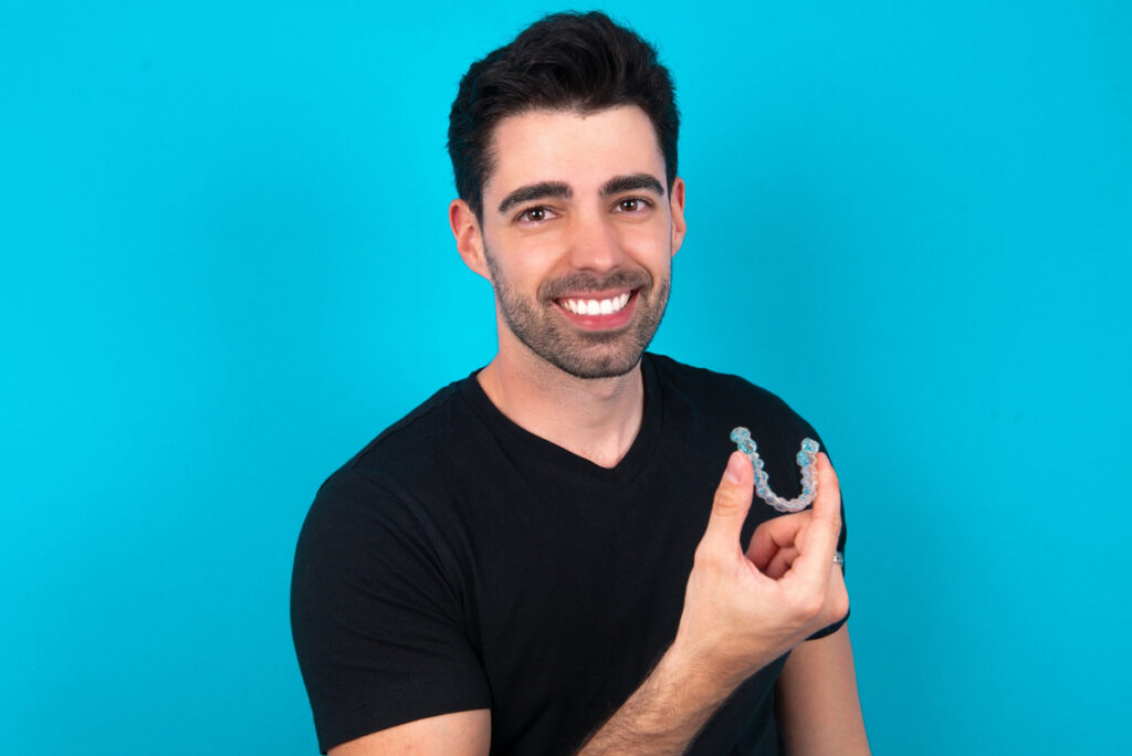 MODEL holding an invisible aligner ready to use it. Dental healthcare and confidence concept.