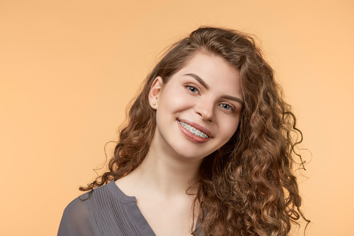 curly hair woman with brackets on biege background