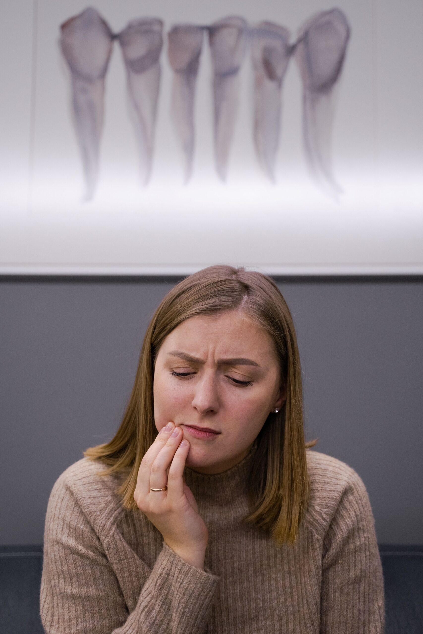 Adult woman holding her cheek in pain from dental emergency in Reno NV